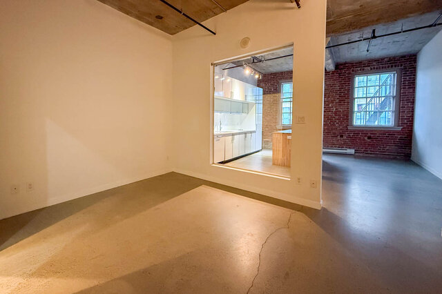 Spacious open-concept loft with concrete floors, exposed brick, and a view into the kitchen. - 308 - 546 Beatty Street, Vancouver Downtown