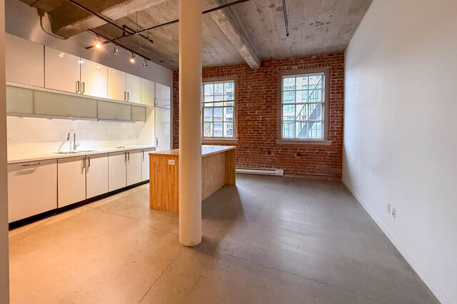 Bright kitchen with white cabinets and brick wall, perfect for downtown living. - 308 - 546 Beatty Street, Vancouver Downtown