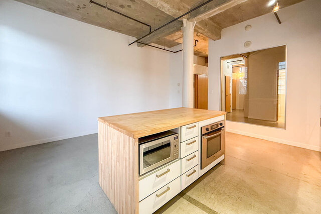 Modern kitchen with light wood countertops and white cabinetry in a spacious downtown loft. - 308 - 546 Beatty Street, Vancouver Downtown