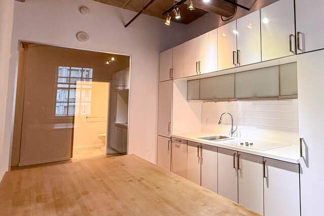 Bright kitchen with white cabinets, hardwood floors, and a city view through the glass door. - 308 - 546 Beatty Street, Vancouver Downtown
