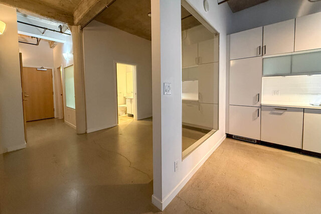 Modern open-concept loft with sleek white cabinets and concrete flooring. - 308 - 546 Beatty Street, Vancouver Downtown