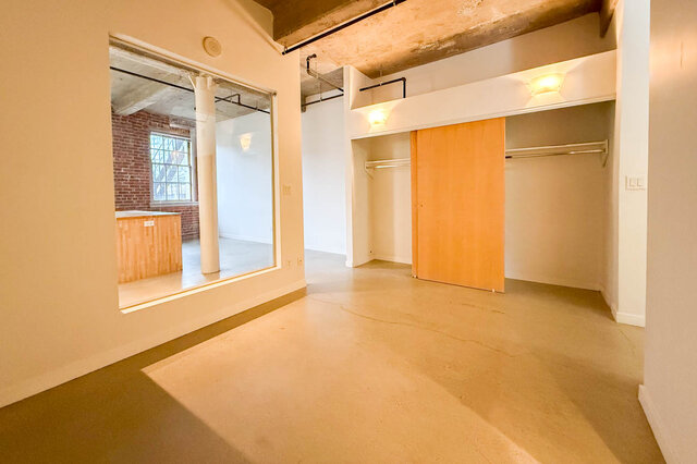 Spacious loft with exposed brick and concrete ceiling, featuring a large closet and hardwood floors. - 308 - 546 Beatty Street, Vancouver Downtown