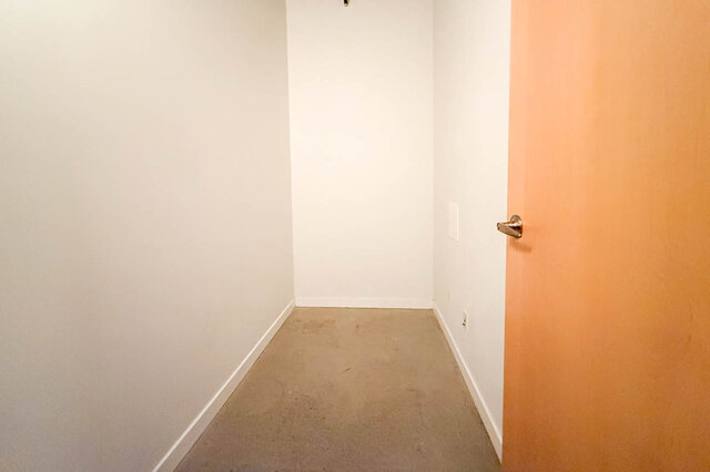 Modern loft bedroom with white walls and orange accent wall, featuring a small closet and carpeted floor.