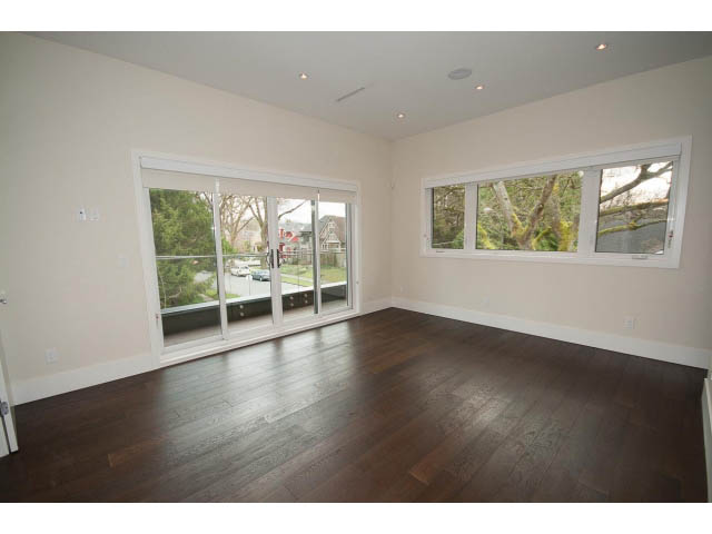 Spacious living room with hardwood floors and large windows showing a city view. - 2895 Balaclava St., Vancouver West Side