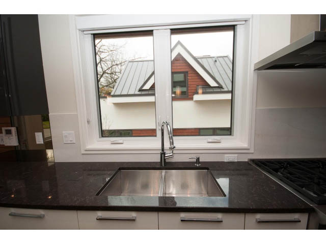 Bright kitchen with granite countertops and a view of a house through the window. - 2895 Balaclava St., Vancouver West Side