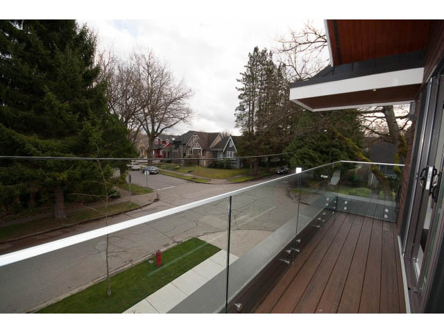 Balcony with glass railing, wooden deck, and view of trees and houses. - 2895 Balaclava St., Vancouver West Side
