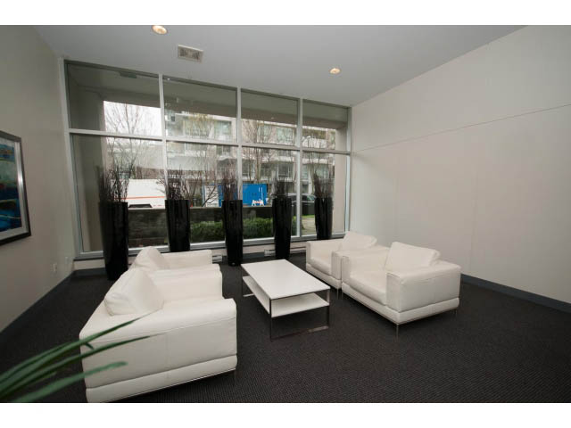 Bright living room with modern white furniture and large windows offering a city view. - 901 - 1690 West 8th Ave, Vancouver West Side