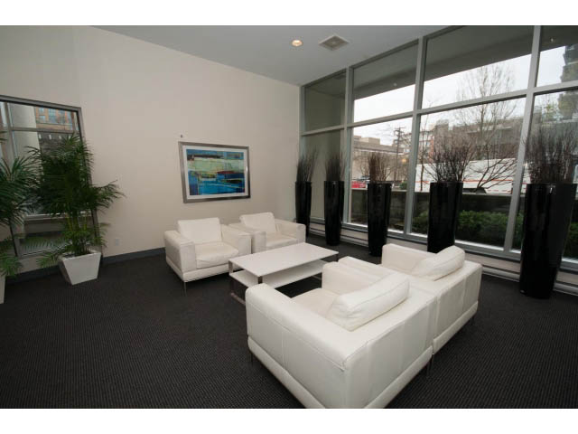 Bright living room with white furniture and large windows showing city view. - 901 - 1690 West 8th Ave, Vancouver West Side