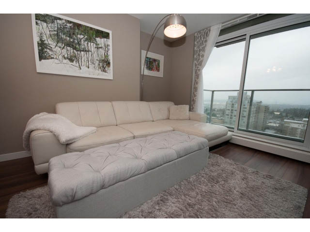 Bright living room with plush rug, city view, and modern decor. - 1602 - 135 East 17th Street, North Vancouver