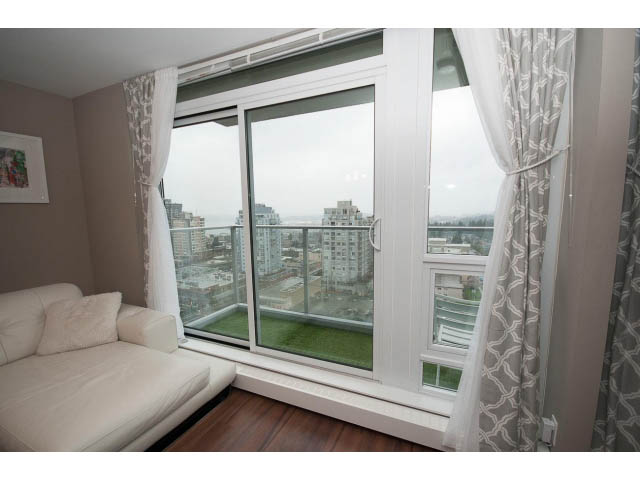 Furnished living room with large windows offering a city view and hardwood floors. - 1602 - 135 East 17th Street, North Vancouver