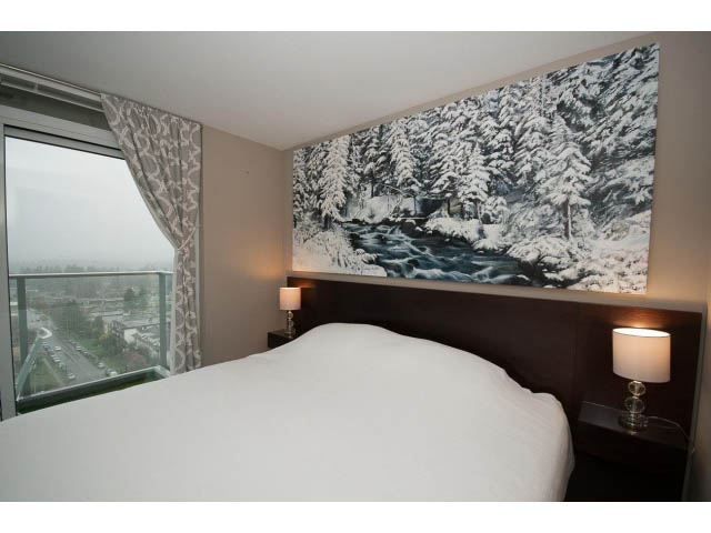 Furnished 1-bedroom condo with a cozy bed, snowy forest mural, and city view from the balcony. - 1602 - 135 East 17th Street, North Vancouver