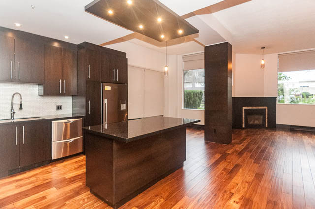 Bright kitchen with dark wood cabinets, hardwood floors, and a city view. - 102 - 1970 Haro St, Vancouver Downtown