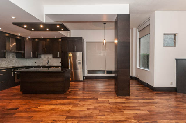 Bright kitchen with dark wood cabinets, stainless steel appliances, and hardwood floors. - 102 - 1970 Haro St, Vancouver Downtown