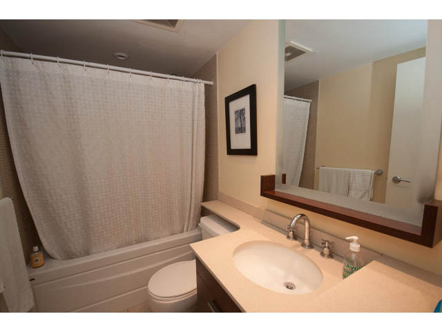 Bright bathroom with white countertop and modern sink, featuring a bathtub with a shower curtain. - 2006 - 583 Beach Crescent, Vancouver Downtown