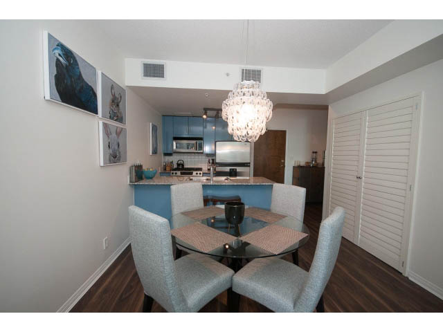Furnished dining area with glass table, light blue cabinets, and hardwood floors. - 906 - 168 Esplanade, North Vancouver