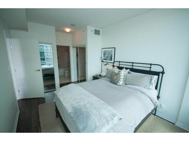 Furnished 1-bedroom + den with hardwood floors and a cozy bed setup. - 906 - 168 Esplanade, North Vancouver