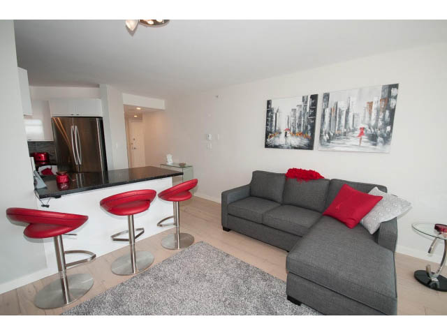 Furnished living room with gray sofa, red cushions, and cityscape art. - 1502 - 907 Beach Ave, Vancouver Downtown