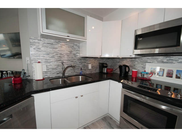 Bright kitchen with modern white cabinetry, granite countertops, and a city view. - 1502 - 907 Beach Ave, Vancouver Downtown
