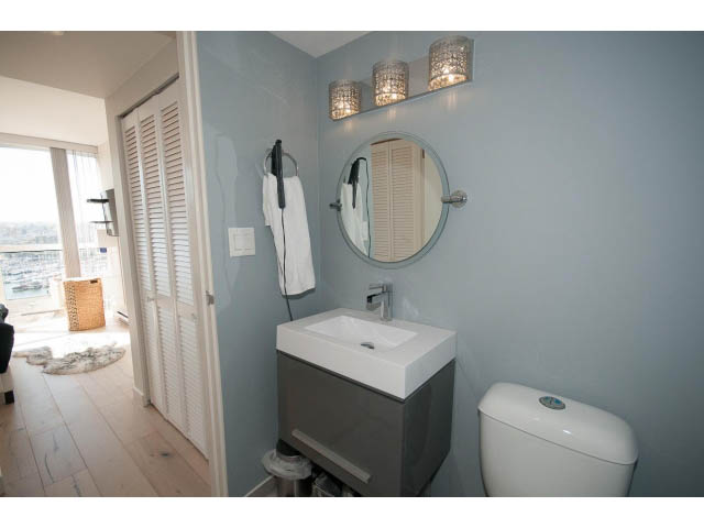 Bright bathroom with light blue walls, modern sink, and city view through sliding doors. - 1502 - 907 Beach Ave, Vancouver Downtown