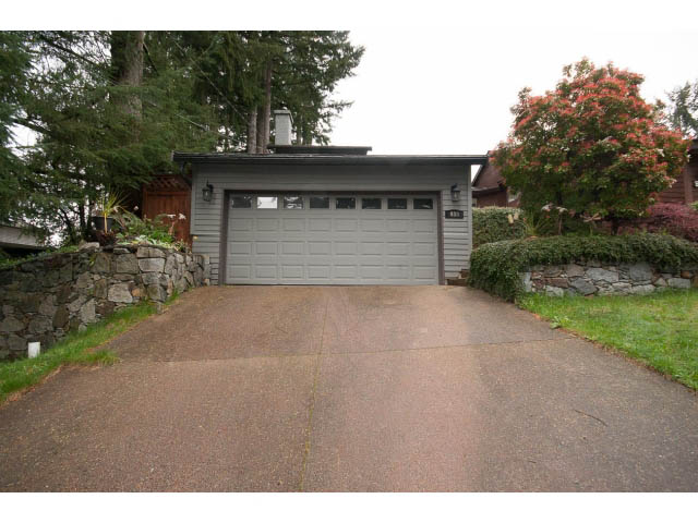 Garage with stone wall and trees in background. - Main - 980 Montroyal Blvd, North Vancouver
