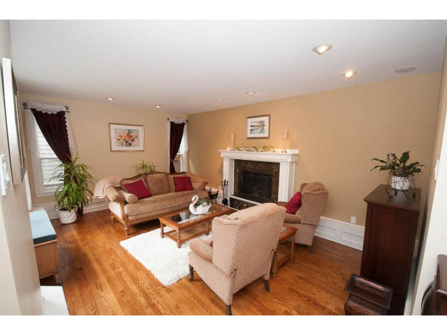 Living room with hardwood floors, cozy seating, and a fireplace. - Main - 980 Montroyal Blvd, North Vancouver