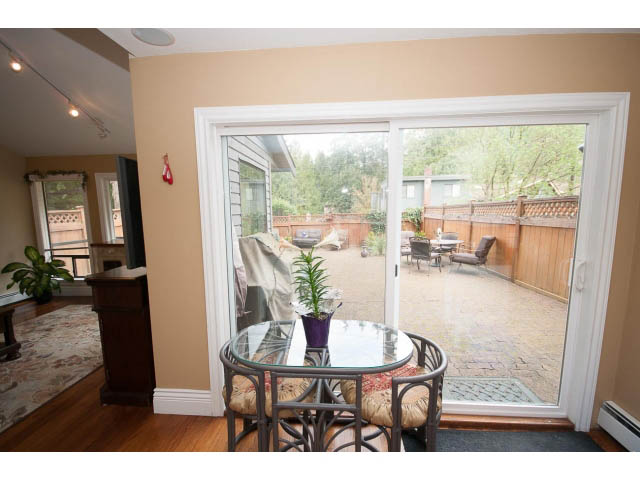 Furnished dining area with glass table, hardwood floors, and sliding glass door leading to patio. - Main - 980 Montroyal Blvd, North Vancouver