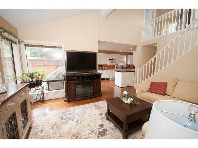 Living room with hardwood floors, a floral rug, and a view of the kitchen. - Main - 980 Montroyal Blvd, North Vancouver