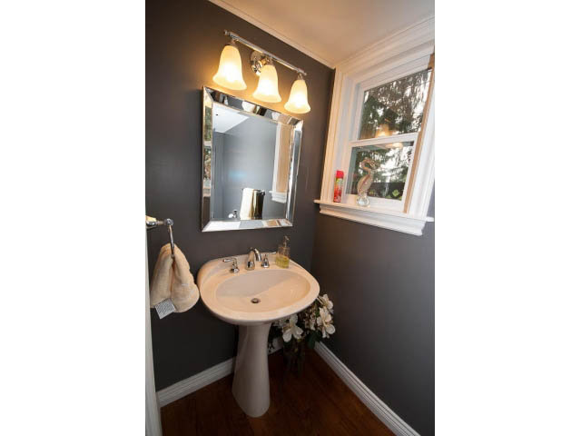 Bathroom with dark walls, pedestal sink, and window view. - Main - 980 Montroyal Blvd, North Vancouver