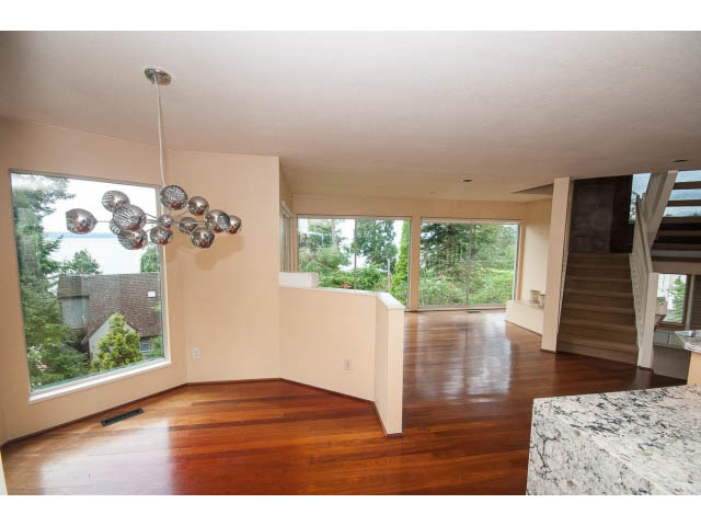 Spacious living room with hardwood floors, large windows, and modern chandelier. - 3890 Sharon Drive, West Vancouver