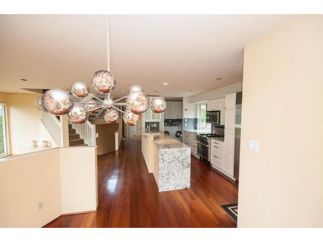 Bright kitchen with hardwood floors and a modern chandelier, featuring a marble island and white cabinetry. - 3890 Sharon Drive, West Vancouver
