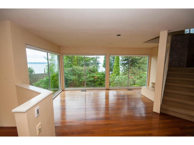 Open living space with hardwood floors and large windows offering a scenic view. - 3890 Sharon Drive, West Vancouver