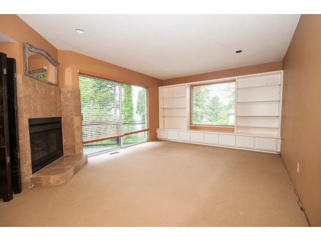 Spacious living room with large windows, fireplace, and built-in shelving. - 3890 Sharon Drive, West Vancouver