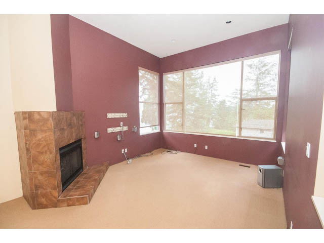 Living room with fireplace, large windows, and carpeted floor. - 3890 Sharon Drive, West Vancouver