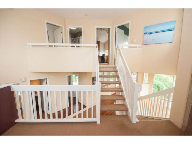 Staircase leading to upper level with white railings and carpeted steps. - 3890 Sharon Drive, West Vancouver