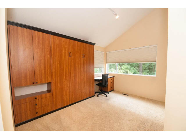 Bright bedroom with built-in wooden cabinets and large windows, allowing natural light. - 3890 Sharon Drive, West Vancouver