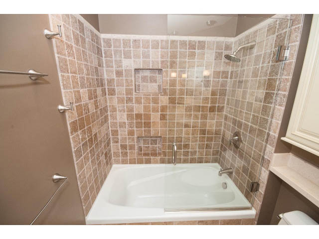 Bright bathroom with tiled walls, glass shower, and white bathtub. - 3890 Sharon Drive, West Vancouver