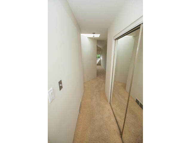 Narrow hallway with carpeted floors and sliding closet doors. - 3890 Sharon Drive, West Vancouver