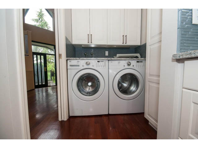 Bright laundry room with white cabinets, hardwood floors, and a city view. - 3890 Sharon Drive, West Vancouver