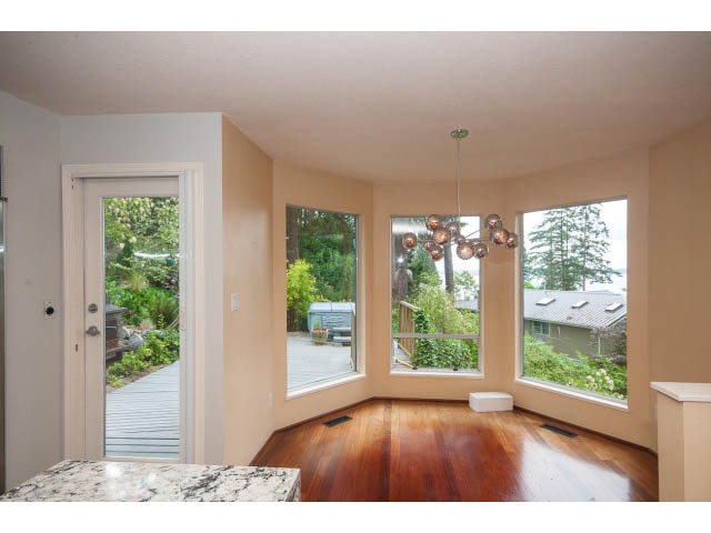 Bright living room with hardwood floors and large windows, showcasing a serene outdoor view. - 3890 Sharon Drive, West Vancouver