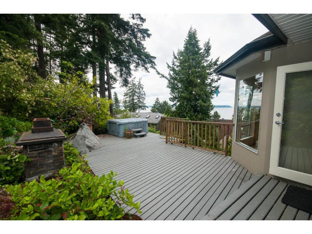 Spacious deck with wooden flooring, ocean view, and lush greenery. - 3890 Sharon Drive, West Vancouver
