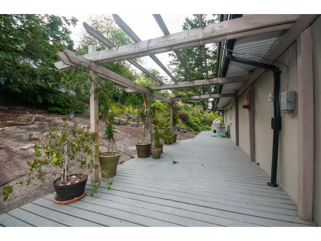 Covered deck with wooden flooring and potted plants. - 3890 Sharon Drive, West Vancouver