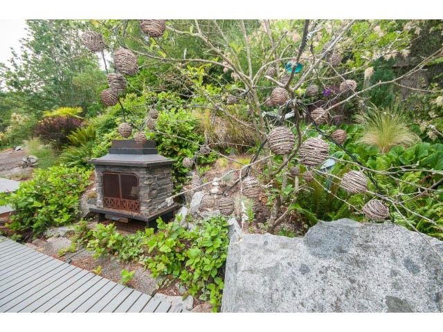 Furnished living space with a rustic outdoor fireplace and woven basket decorations. - 3890 Sharon Drive, West Vancouver