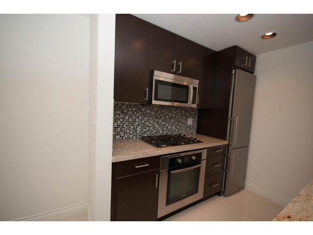 Bright kitchen with granite countertops, stainless steel appliances, and dark cabinetry. - 1101 - 172 Victory Ship Way, North Vancouver