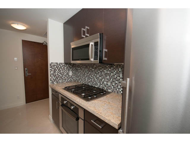 Bright kitchen with granite countertops, stainless steel appliances, and mosaic tile backsplash. - 1101 - 172 Victory Ship Way, North Vancouver