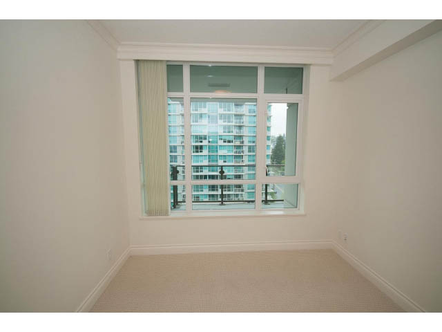 Bright bedroom with large window, city view, and neutral carpeting. - 1101 - 172 Victory Ship Way, North Vancouver