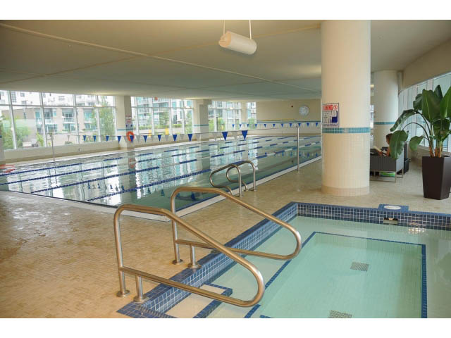 Spacious indoor swimming pool with tiled floors and railings, large windows offering city views. - 1101 - 172 Victory Ship Way, North Vancouver