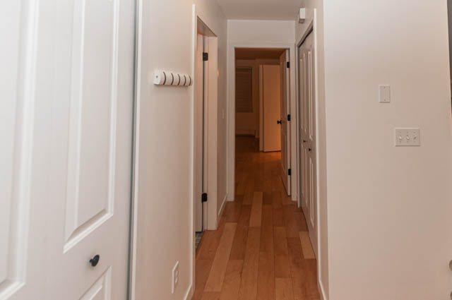 Furnished hallway with white walls and hardwood floors leading to multiple rooms. - 2263 Heather st., Vancouver West Side