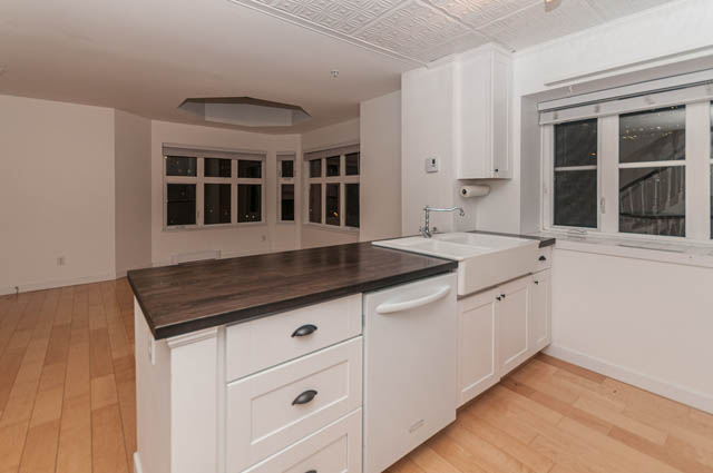 Bright kitchen with white cabinets, dark countertops, and hardwood floors. - 2263 Heather st., Vancouver West Side