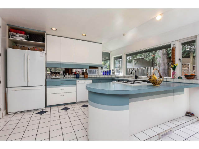 Bright kitchen with white cabinets, blue accents, and a large island. - 3243 Milton Ave., North Vancouver