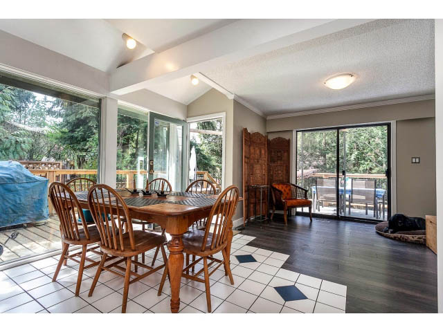 Spacious dining area with wooden furniture and large windows, leading to a patio. - 3243 Milton Ave., North Vancouver